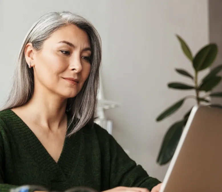 Woman with silver hair working on a laptop