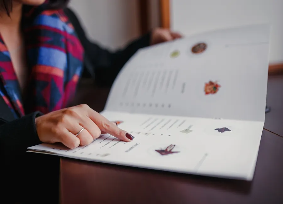 A woman pointing at a restaurant menu in dim light